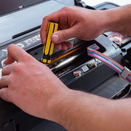 Repairman repairing broken color printer Repairman repairing broken color printer